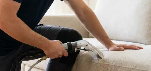 Professional upholstery cleaner deep-cleaning a fabric sofa with a handheld extraction tool, Buffalo, NY.